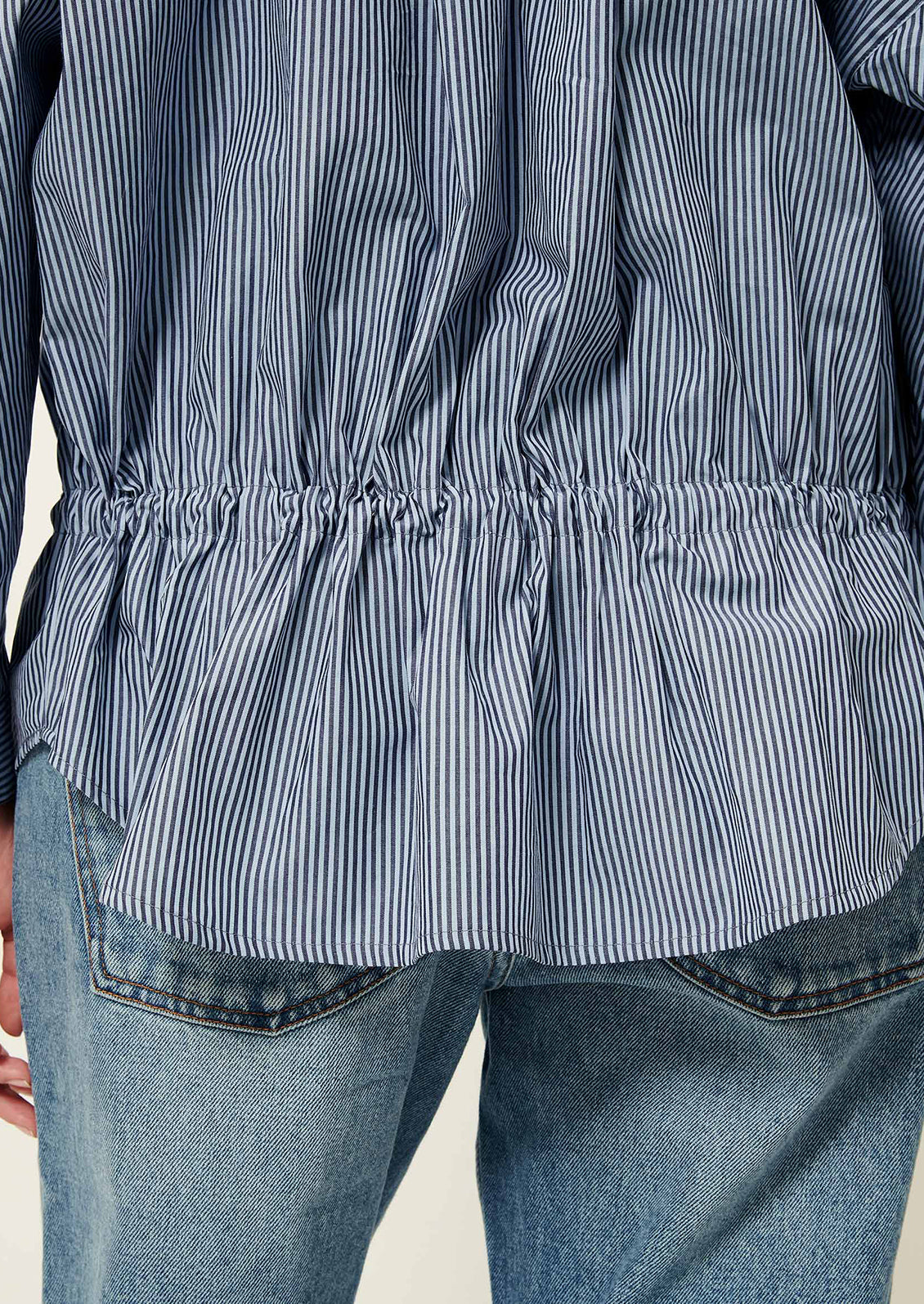 Close-up of a person wearing a blue and white striped shirt with a focus on the waistband.