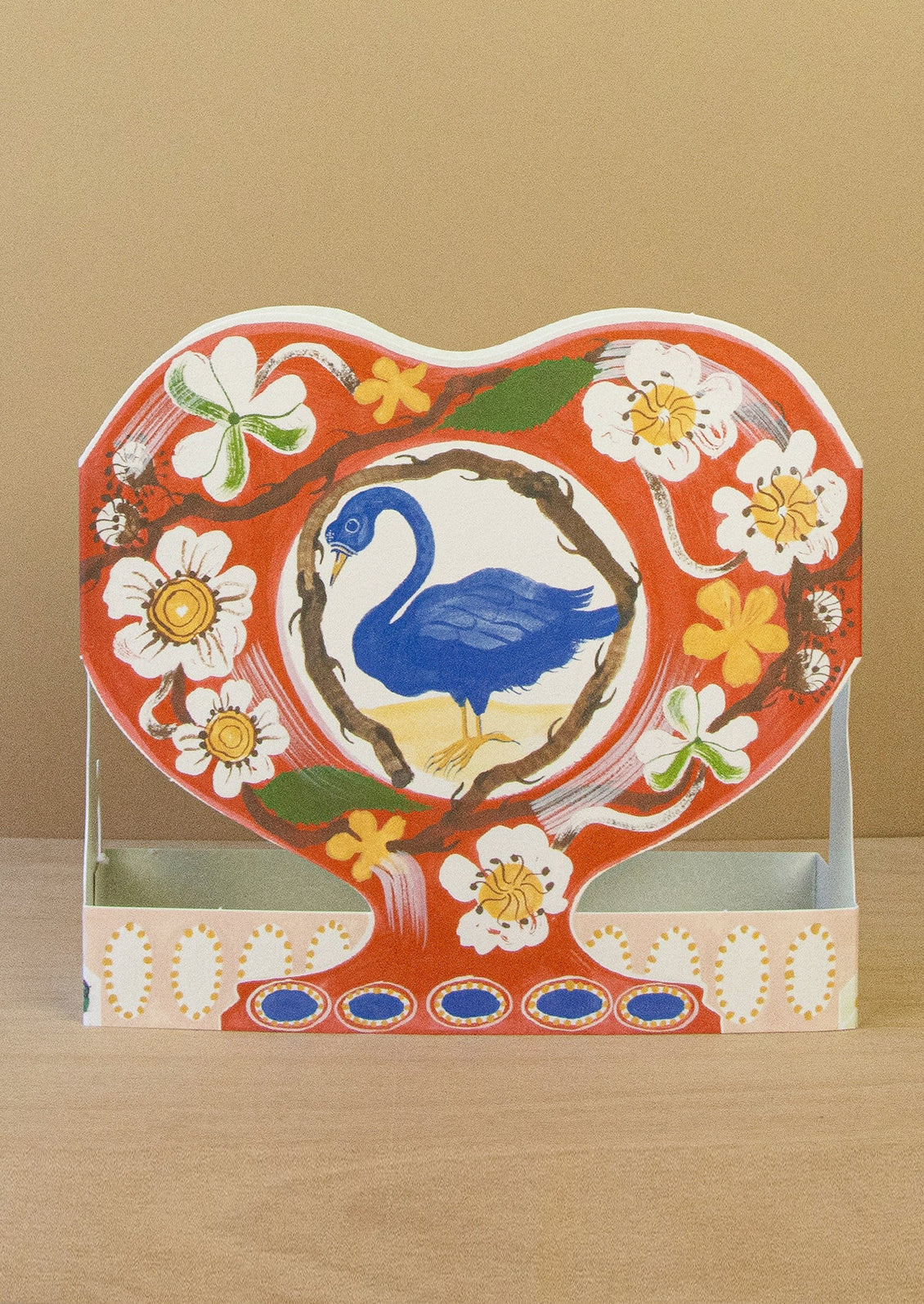 Decorative heart-shaped card with a blue swan and floral design on a beige background