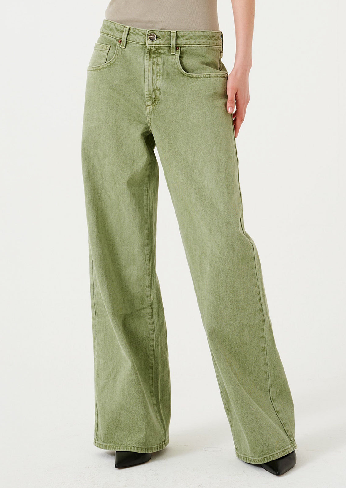 A woman wearing a pair of wide leg jeans in moss green wash.