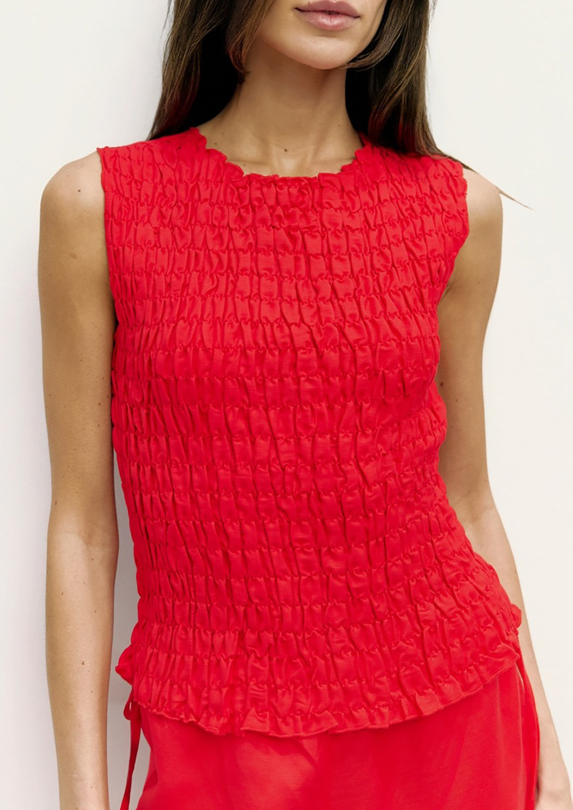 Red textured sleeveless top worn by a model against a white background