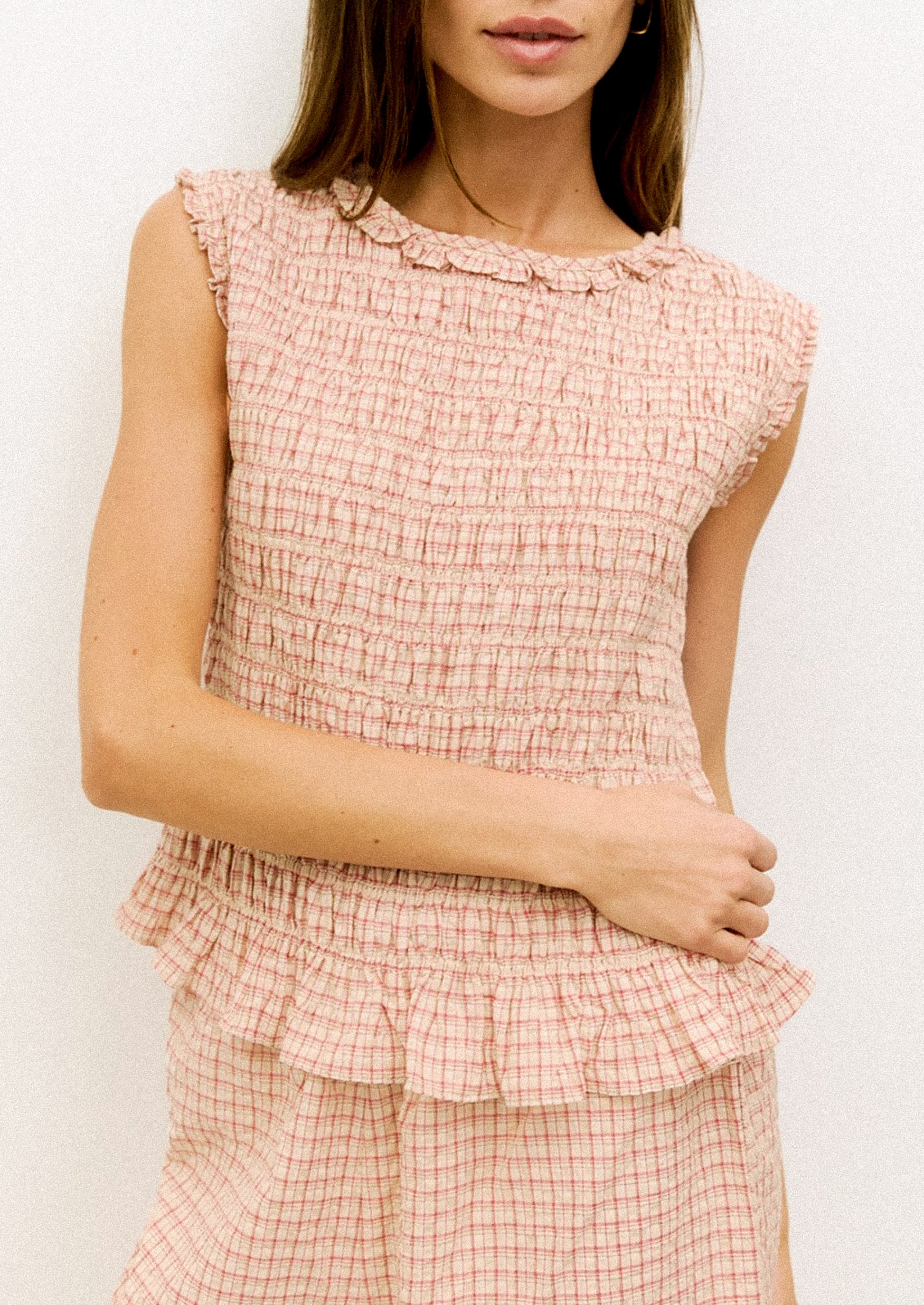 Woman wearing a pink checkered dress against a white background