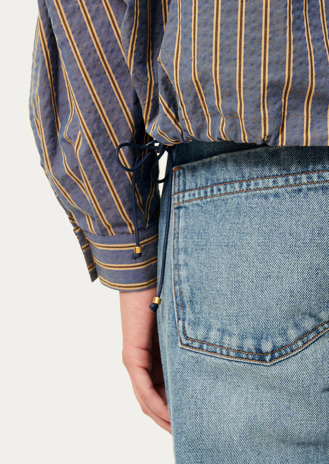 Close-up of a person wearing a striped shirt and jeans on a white background
