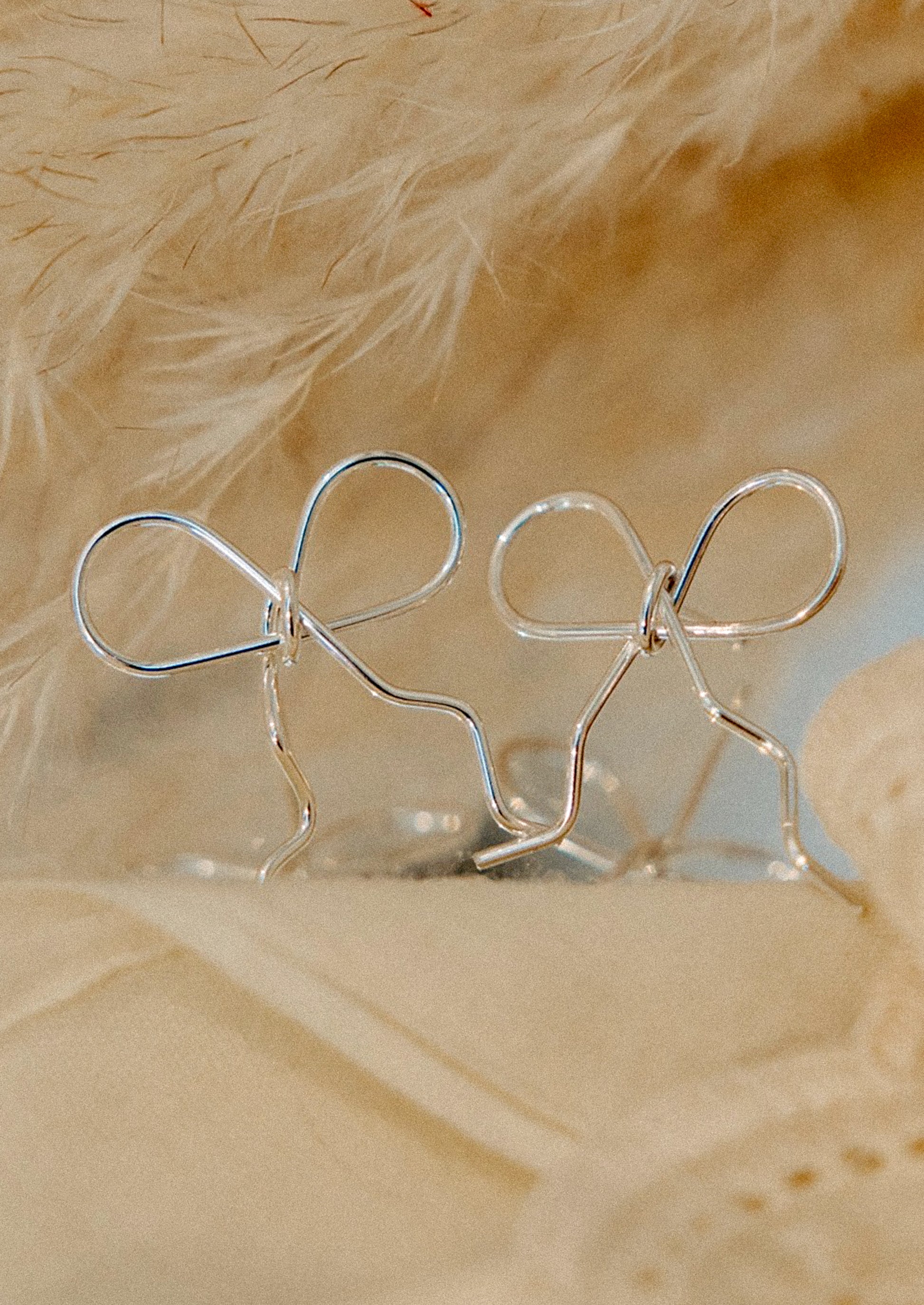 A pair of handmade earrings in bow shape made from sterling silver wire.