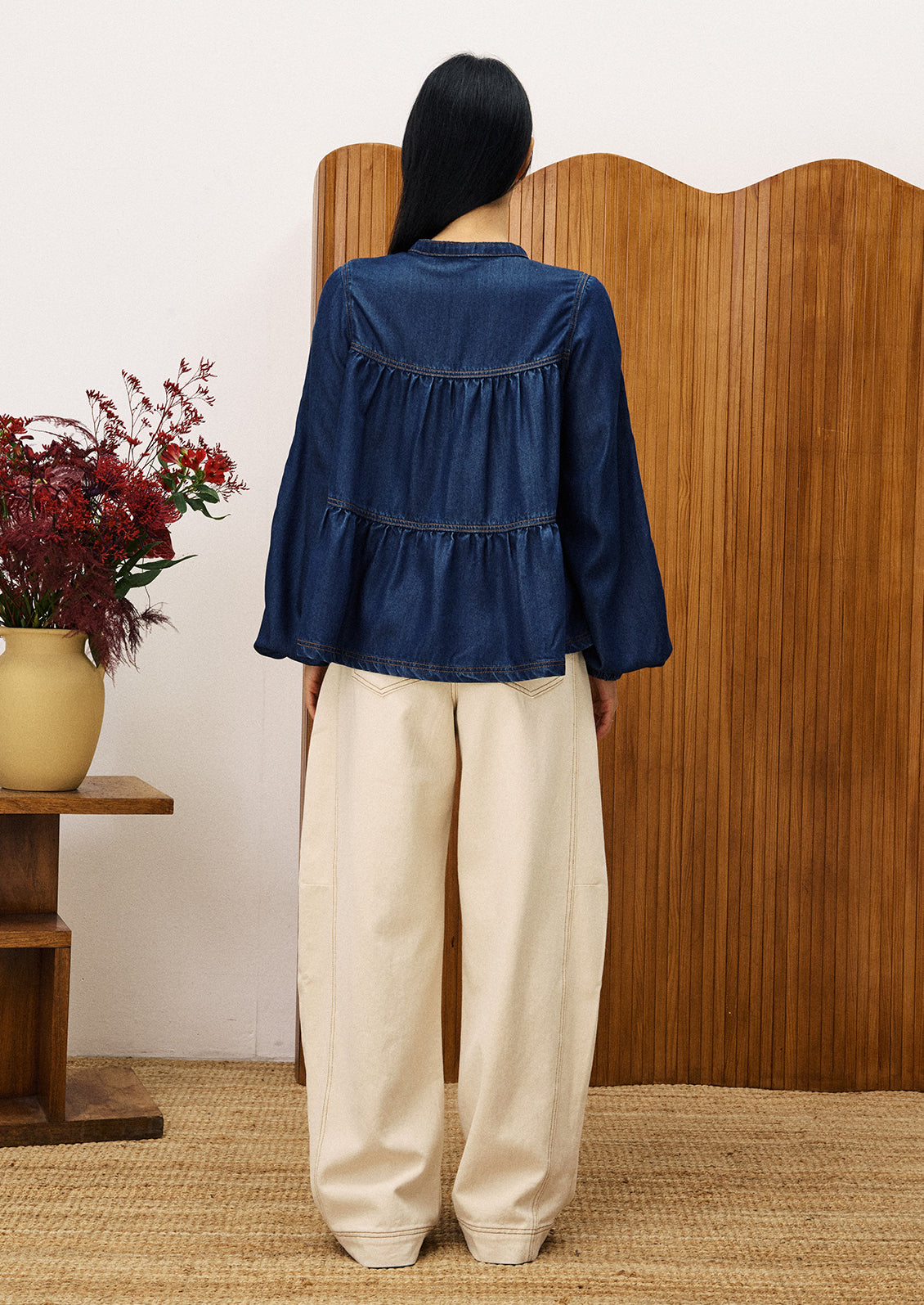 A woman wearing a denim top with shirred ruching.