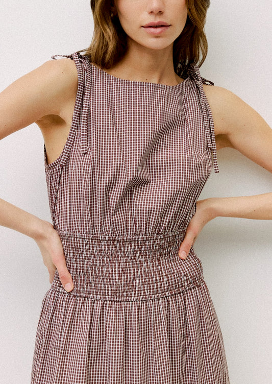Woman wearing a brown checkered dress against a white background