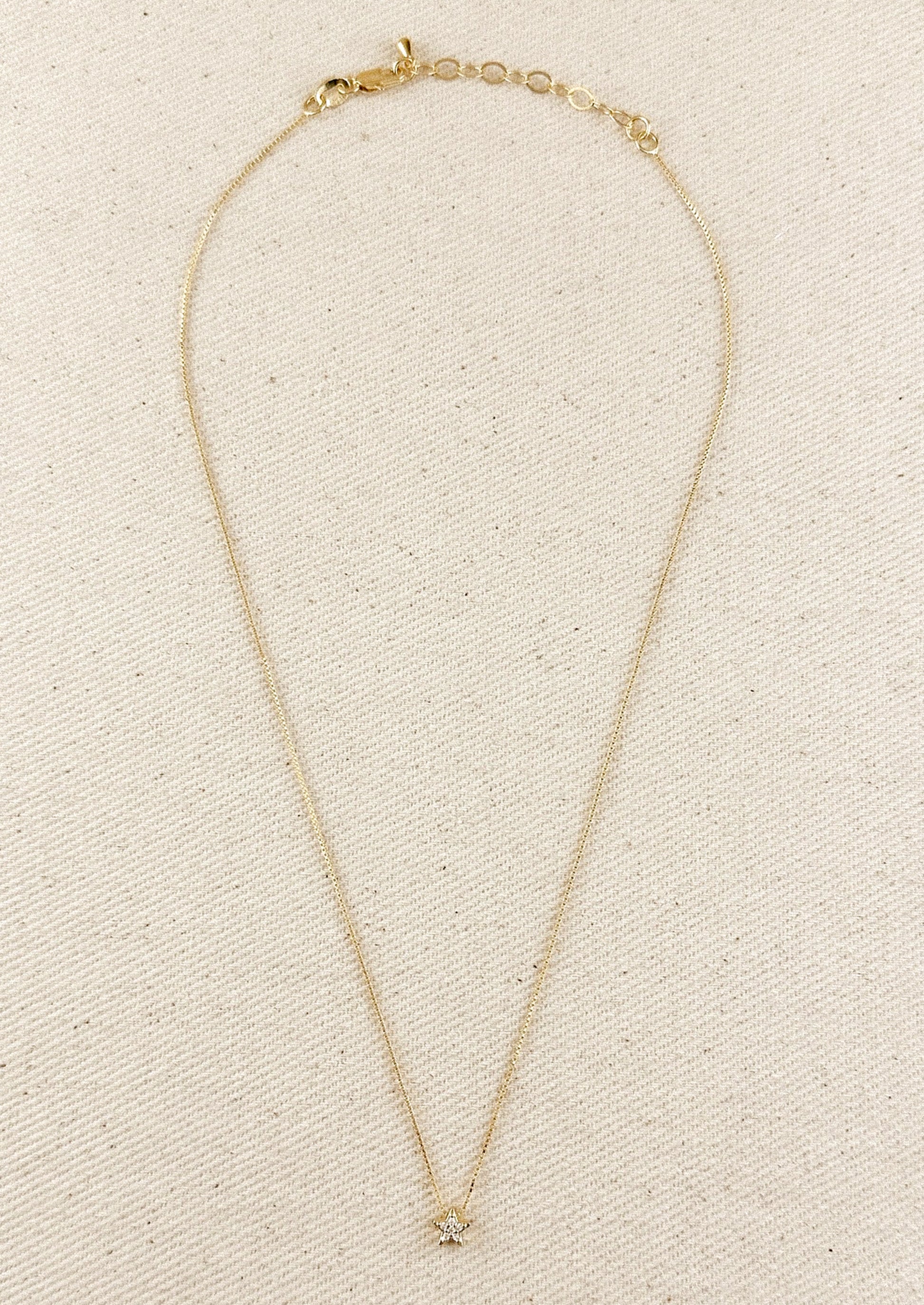 A gold box chain necklace with small gold & crystal star charm.