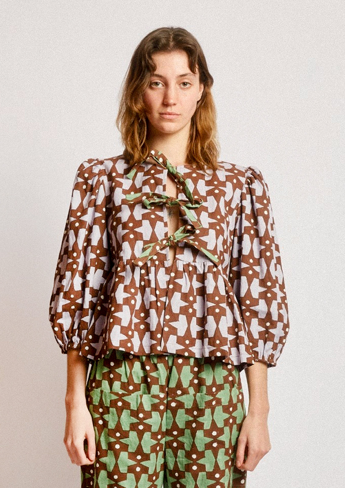 A person wearing a puff sleeve shirt with contrast tie front.