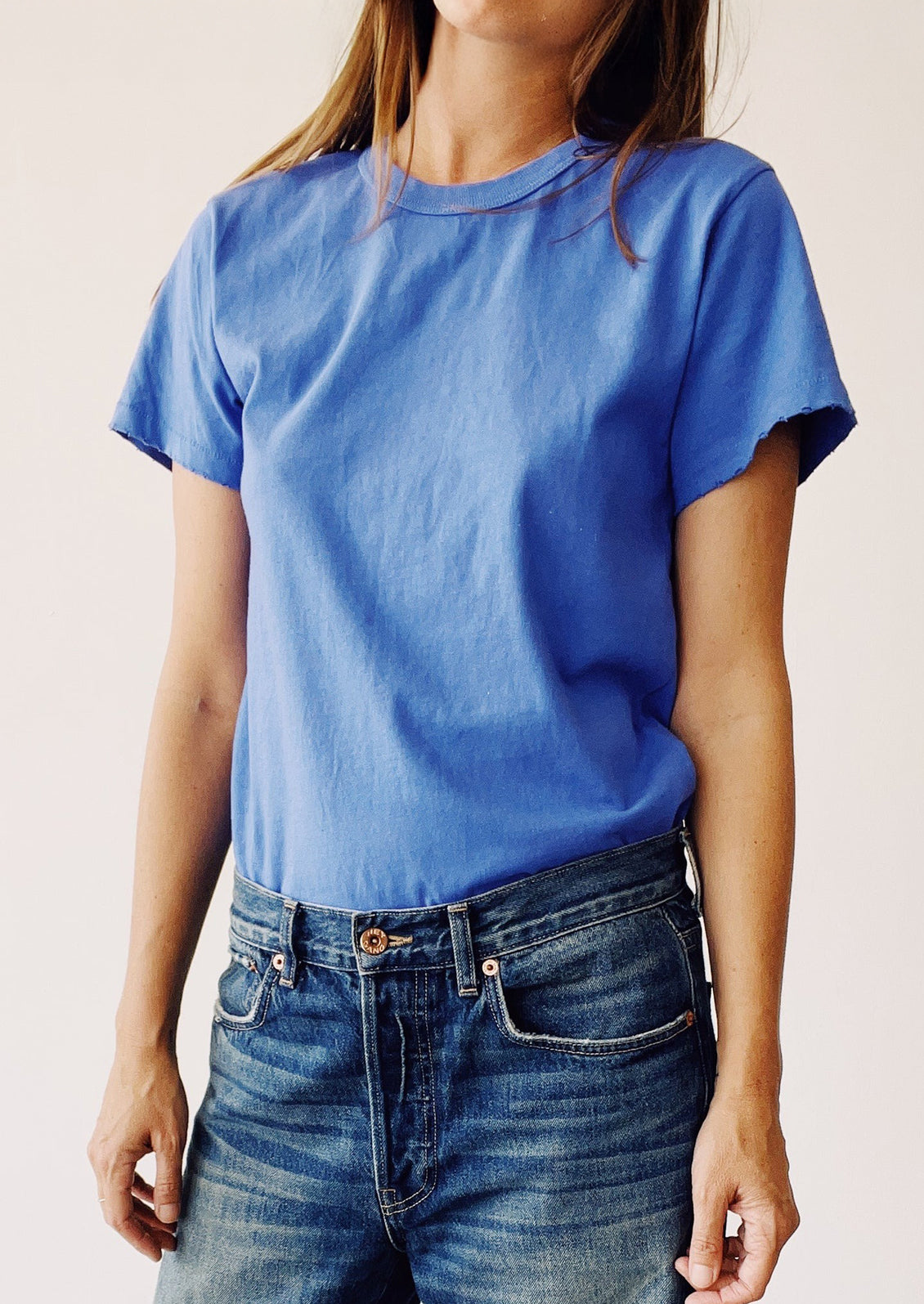 Person wearing a blue t-shirt and jeans against a plain background