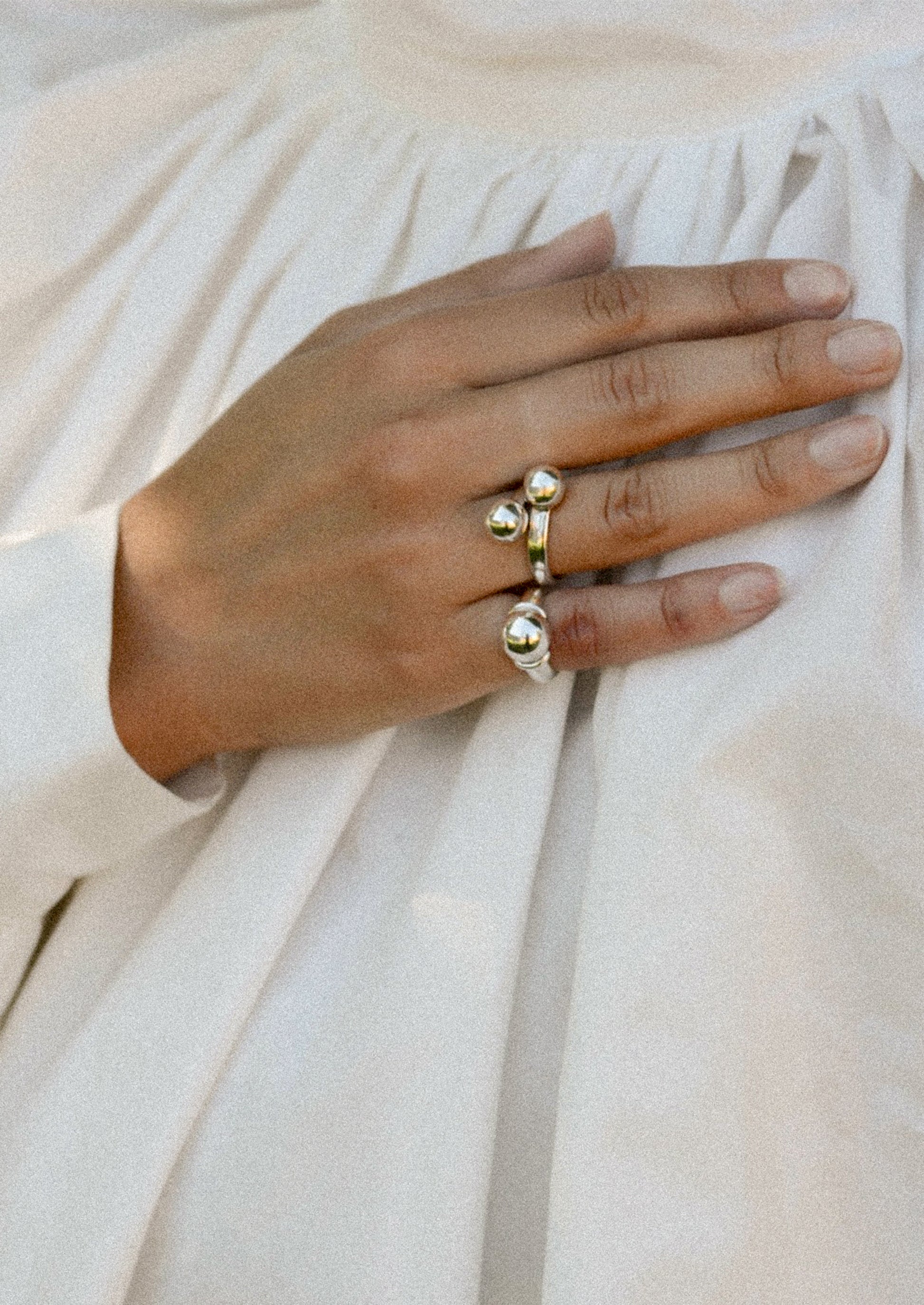 Hand wearing silver rings on a light fabric background