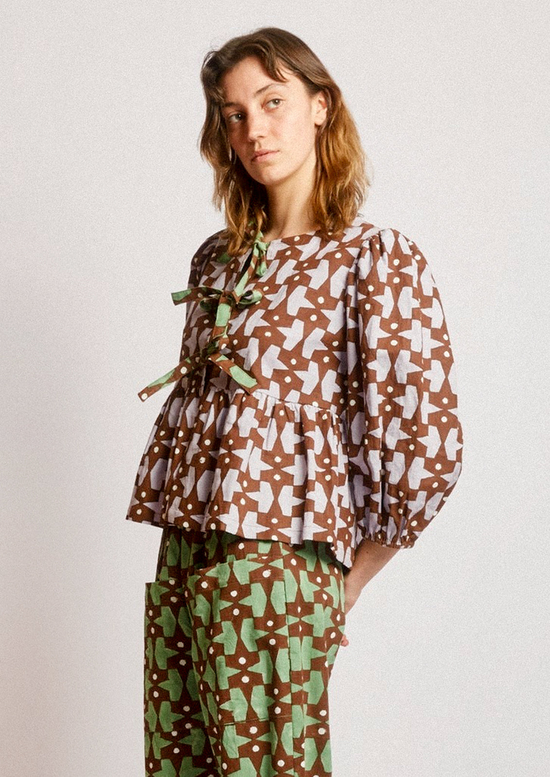 A person wearing a puff sleeve shirt with contrast tie front.