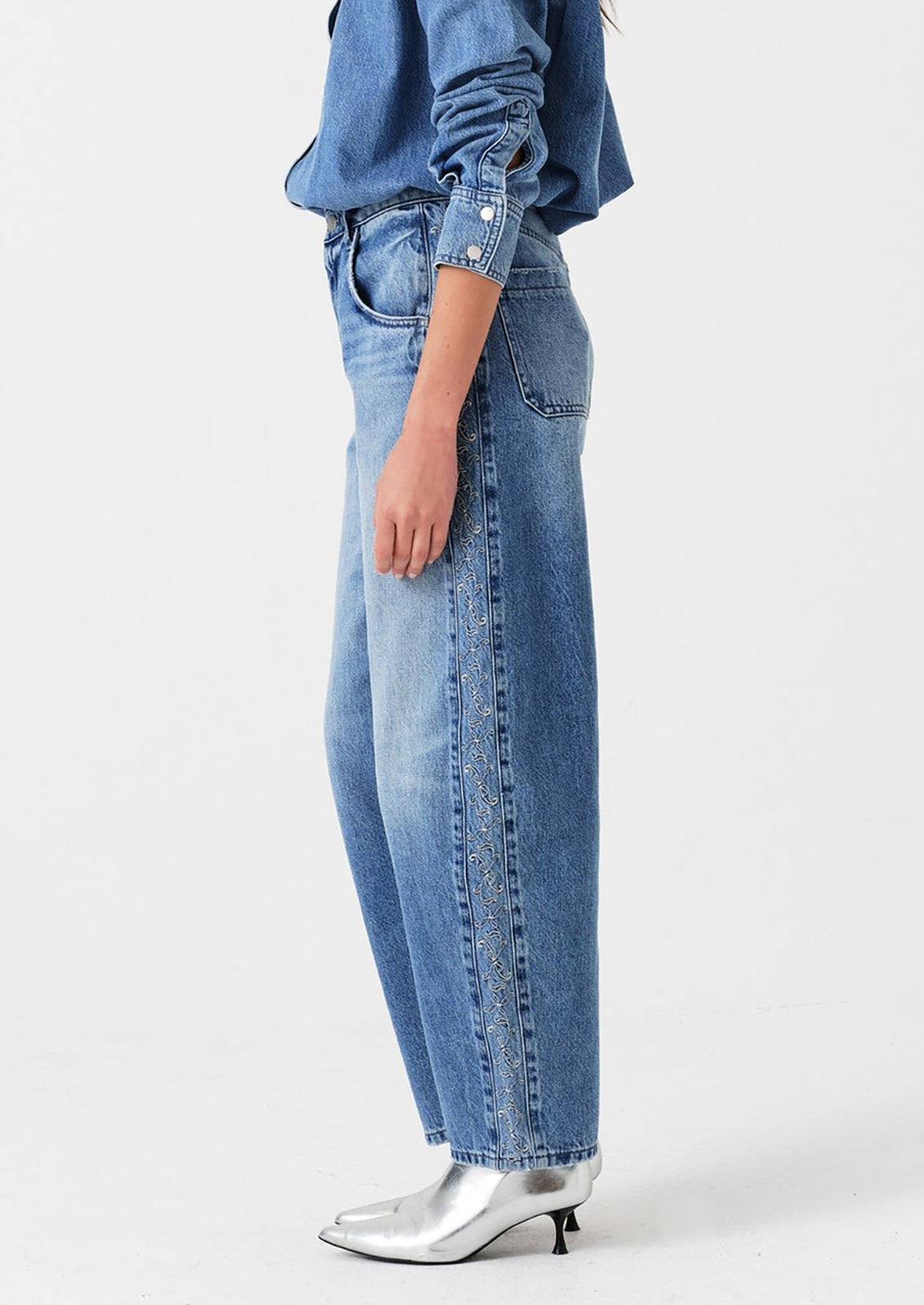 Person wearing light blue jeans and a blue denim shirt on a white background