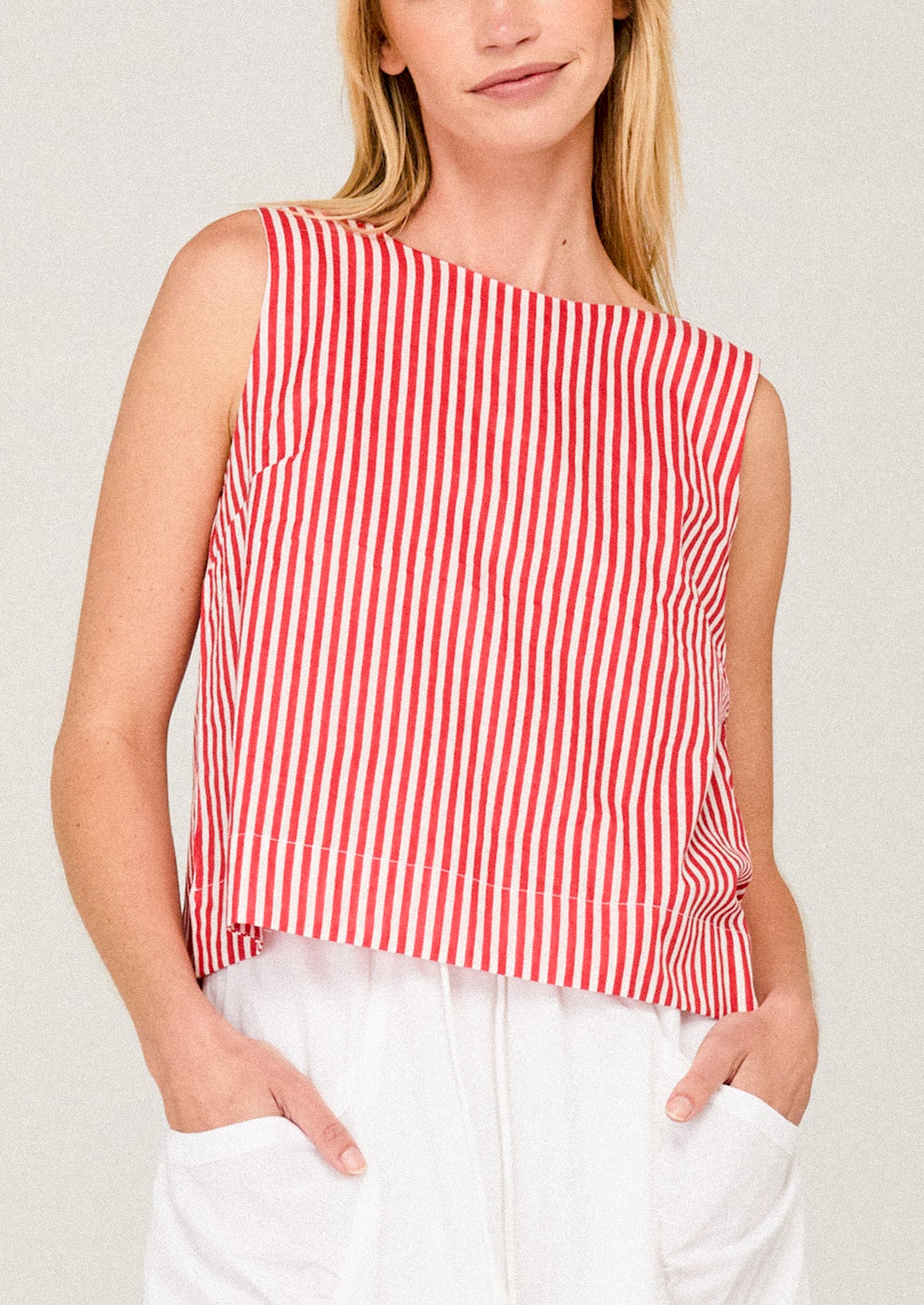 Woman wearing a red and white striped sleeveless top against a plain background