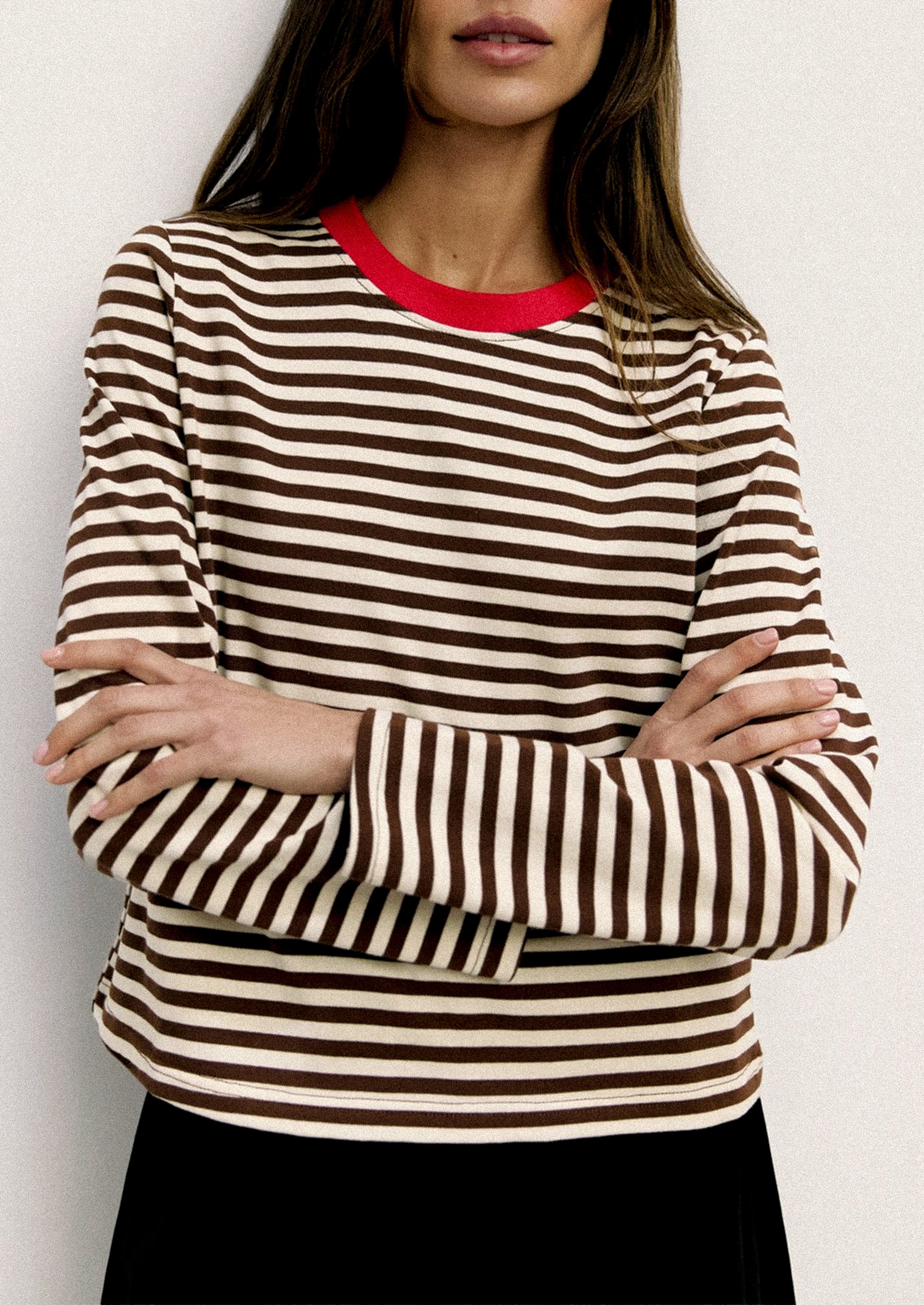 Woman wearing a striped sweater with a red collar against a white background