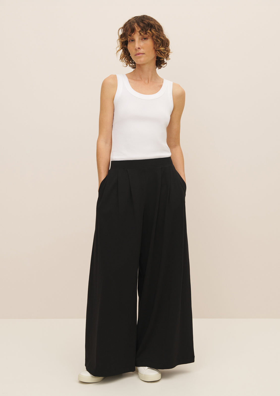 A woman wearing a pair of flowy, wide leg black pants.