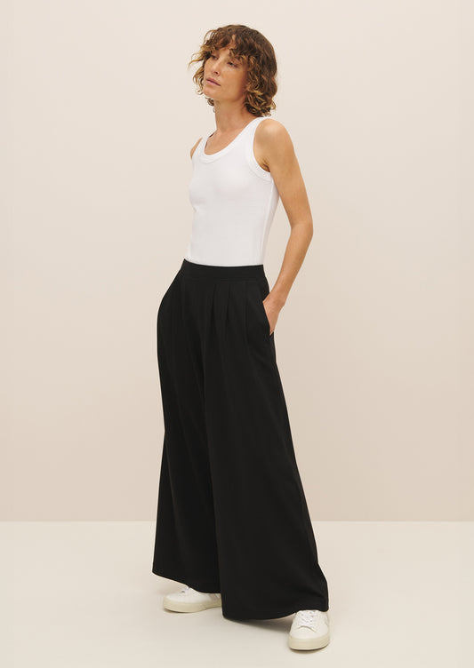 A woman wearing a pair of flowy, wide leg black pants.