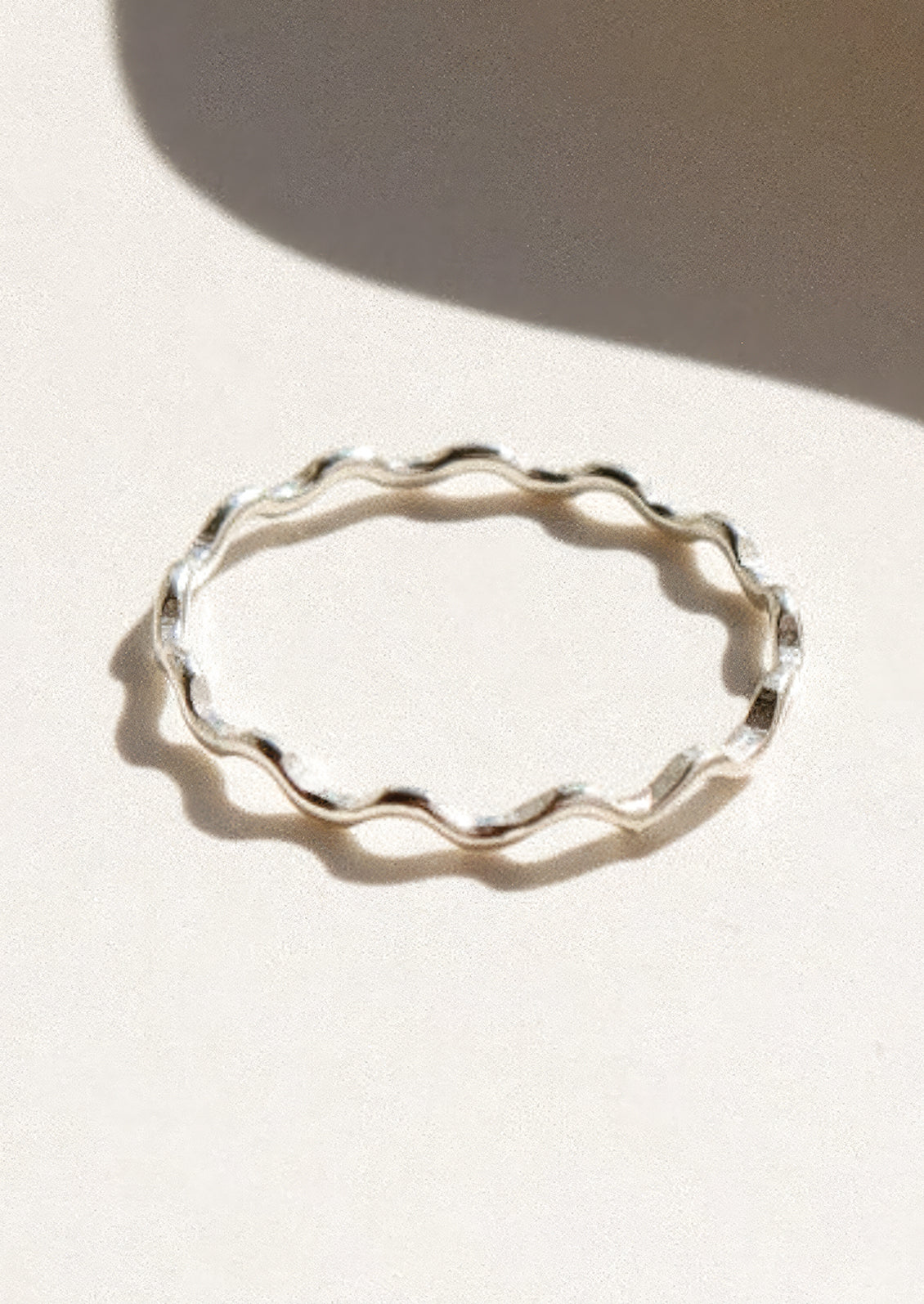 Silver ring with wavy shape on a light background