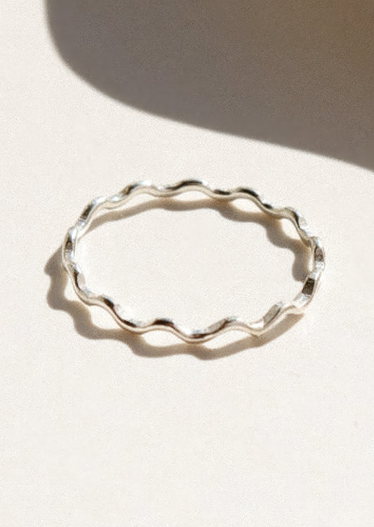Silver ring with wavy shape on a light background