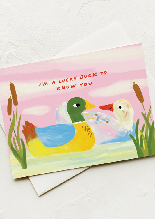 A greeting card with an illustration of two ducks, text reads "I'm a lucky duck to know you"