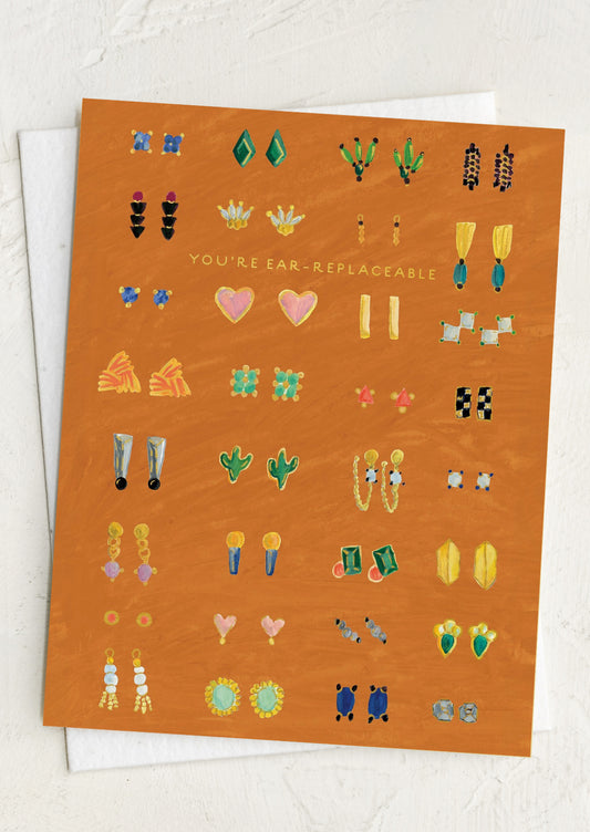 Card with various illustrated earrings on an orange background, text reads "You're Ear-Replaceable".