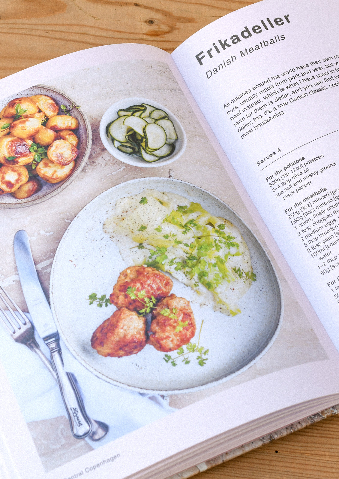 A cookbook open on a table with an image and recipe for danish meatballs.
