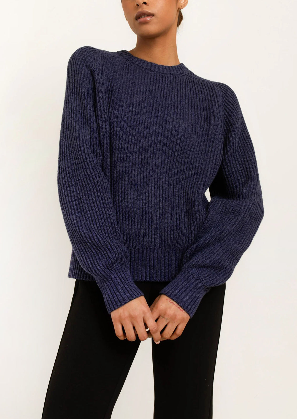 A woman wearing a rib knit sweater in navy blue.