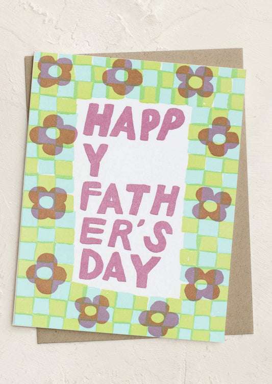 A greeting card with checkered border with flowers, text reads "Happy Father's Day".