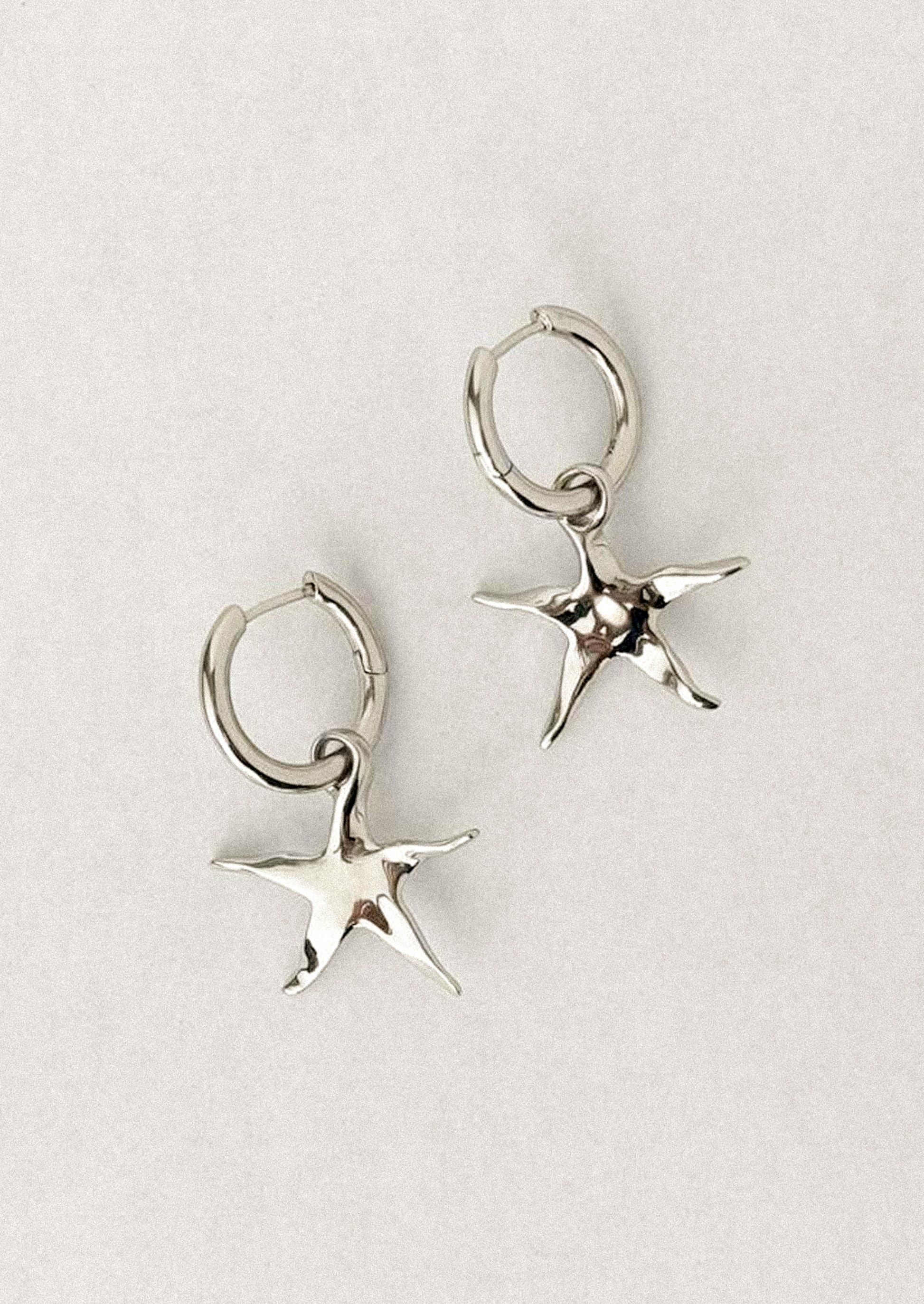A pair of silver star earrings on hoop.