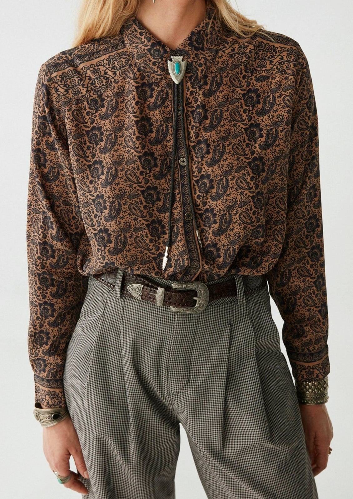 A woman wearing a paisley print blouse in brown and black.