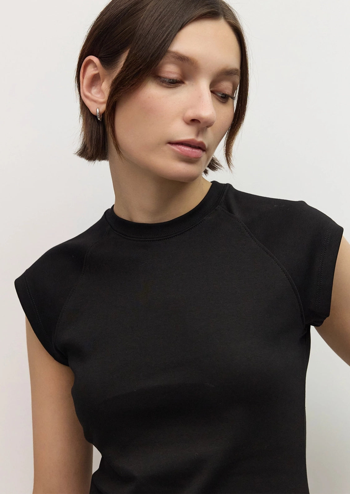 A woman wearing a raglan muscle tee in black.
