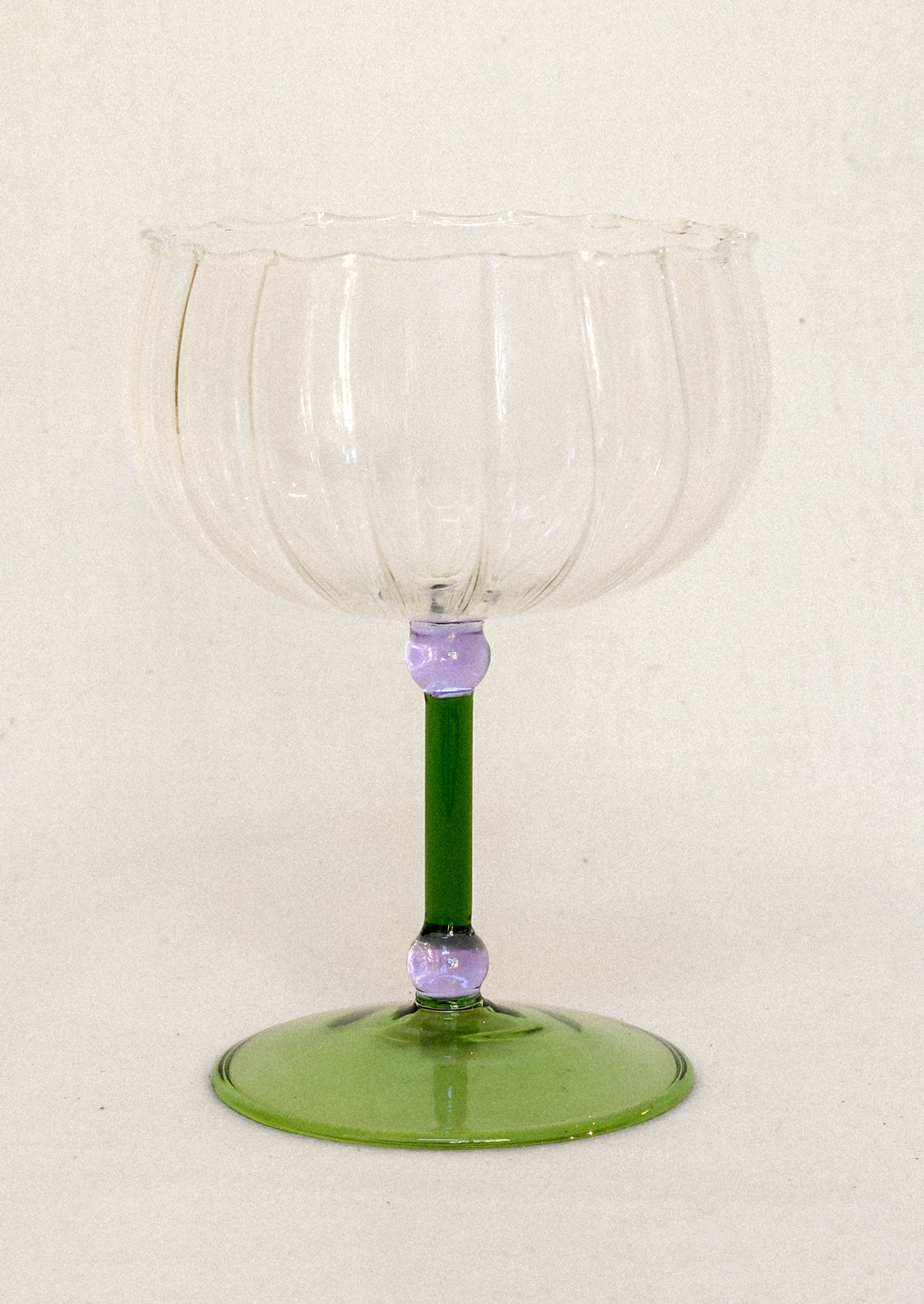 Clear glass coupe with small round purple details and a green stem and base.