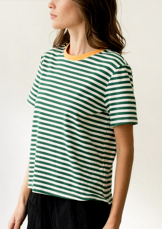 A woman wearing a short sleeve t-shirt in green and white stripes with orange neck trim.