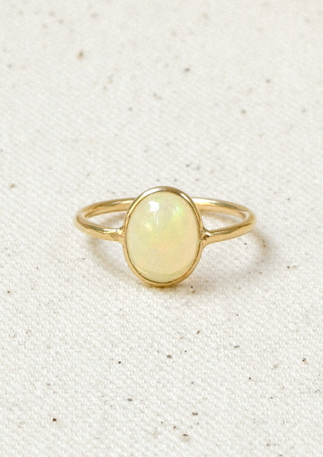 A gold ring with a natural Ethiopian opal bezeled in the center.