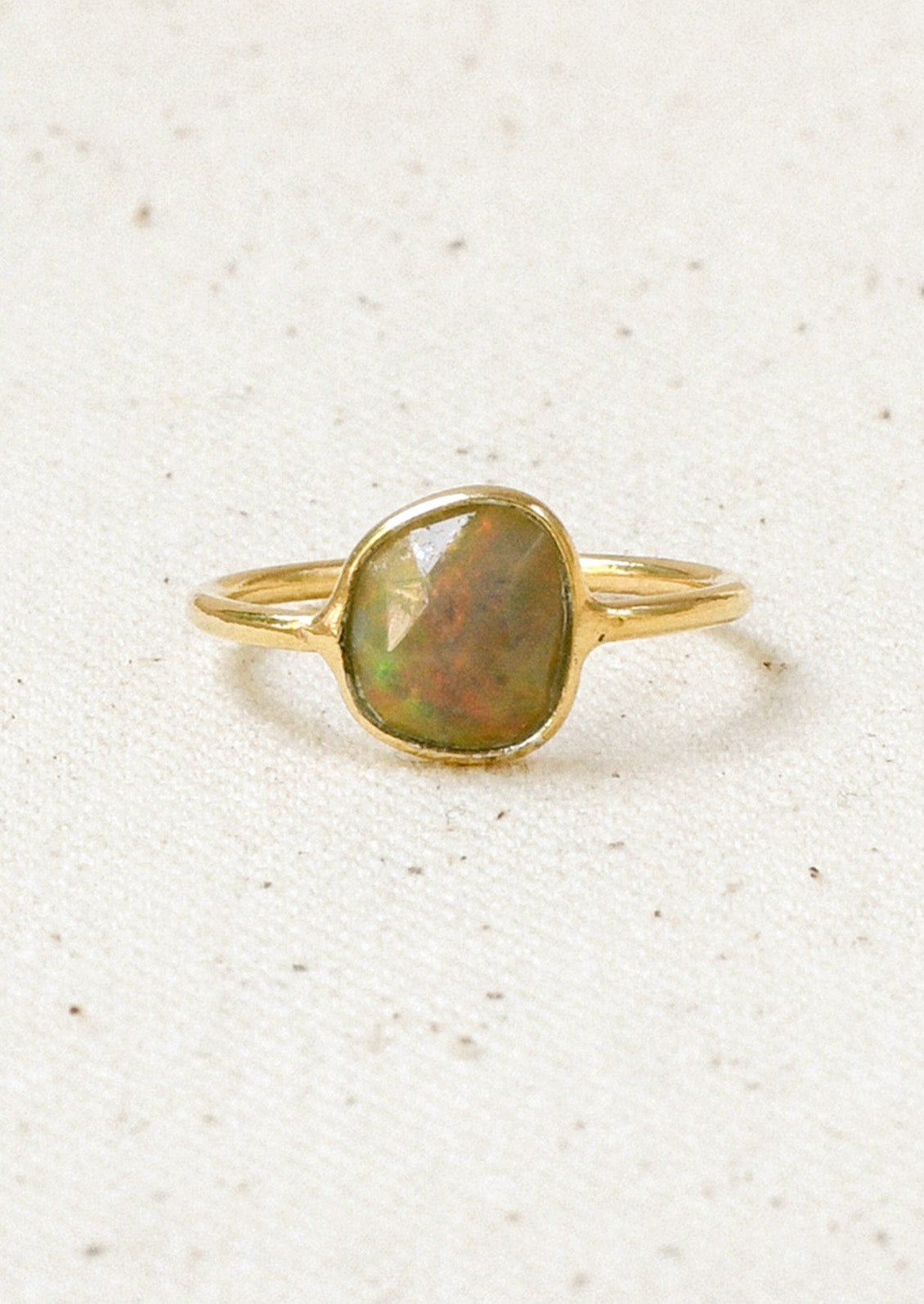 A gold ring with a natural Ethiopian opal bezeled in the center.