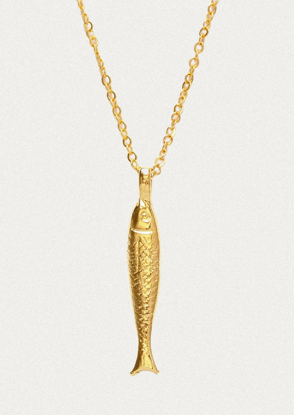 A gold chain necklace with a fish charm.