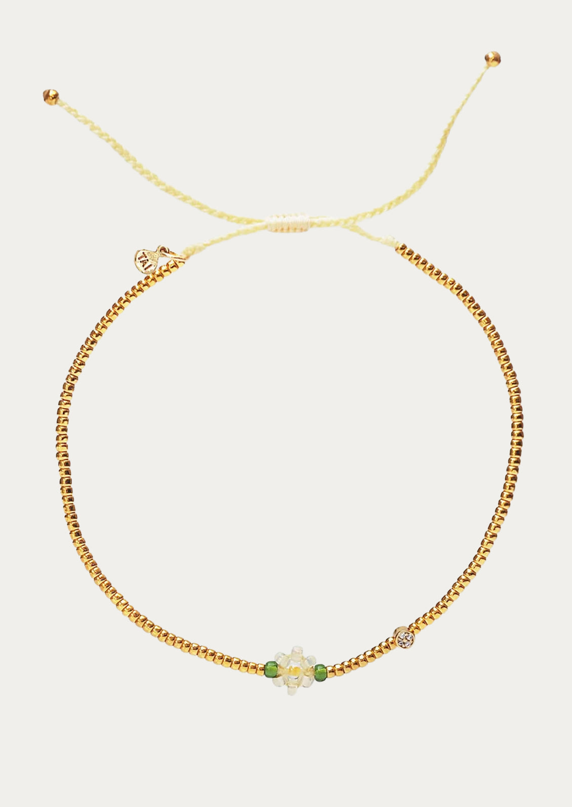 A beaded bracelet in gold and white with beaded flower charm.