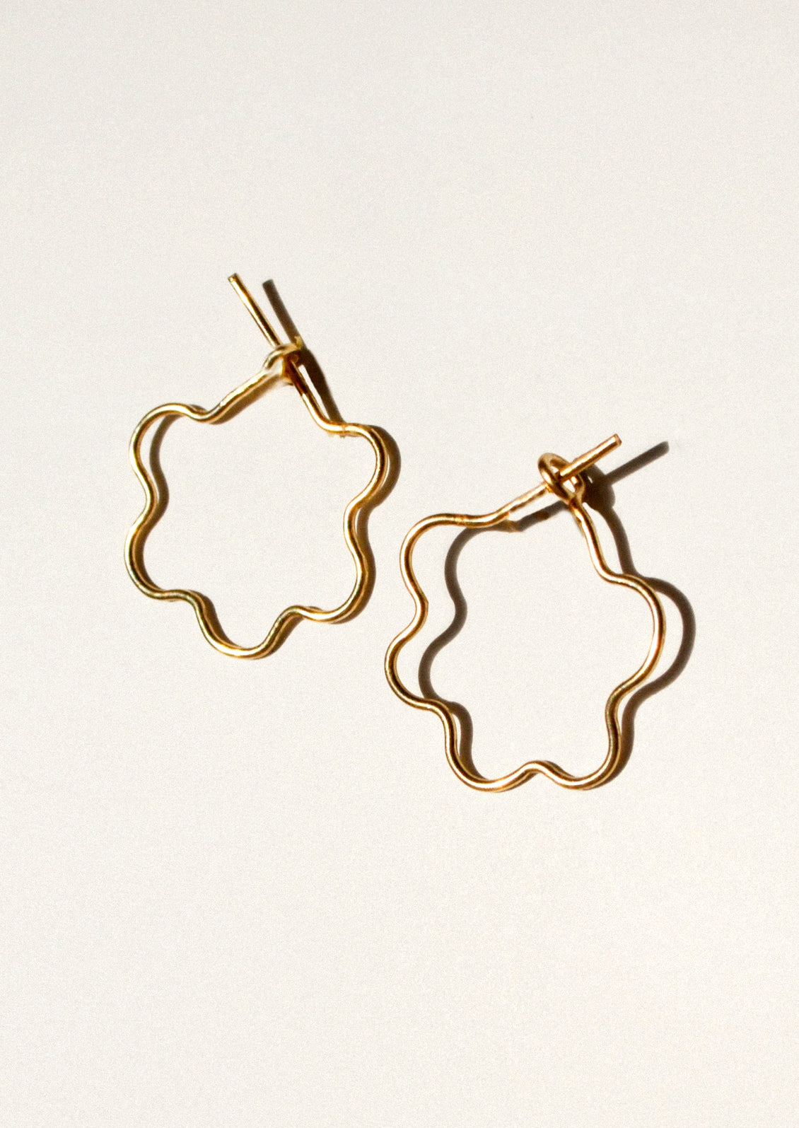 A pair of gold flower shaped hoop earrings.