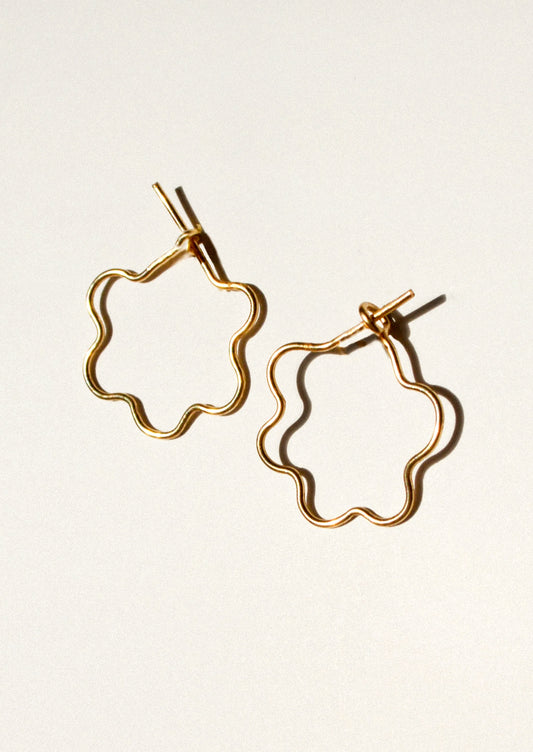 A pair of gold flower shaped hoop earrings.