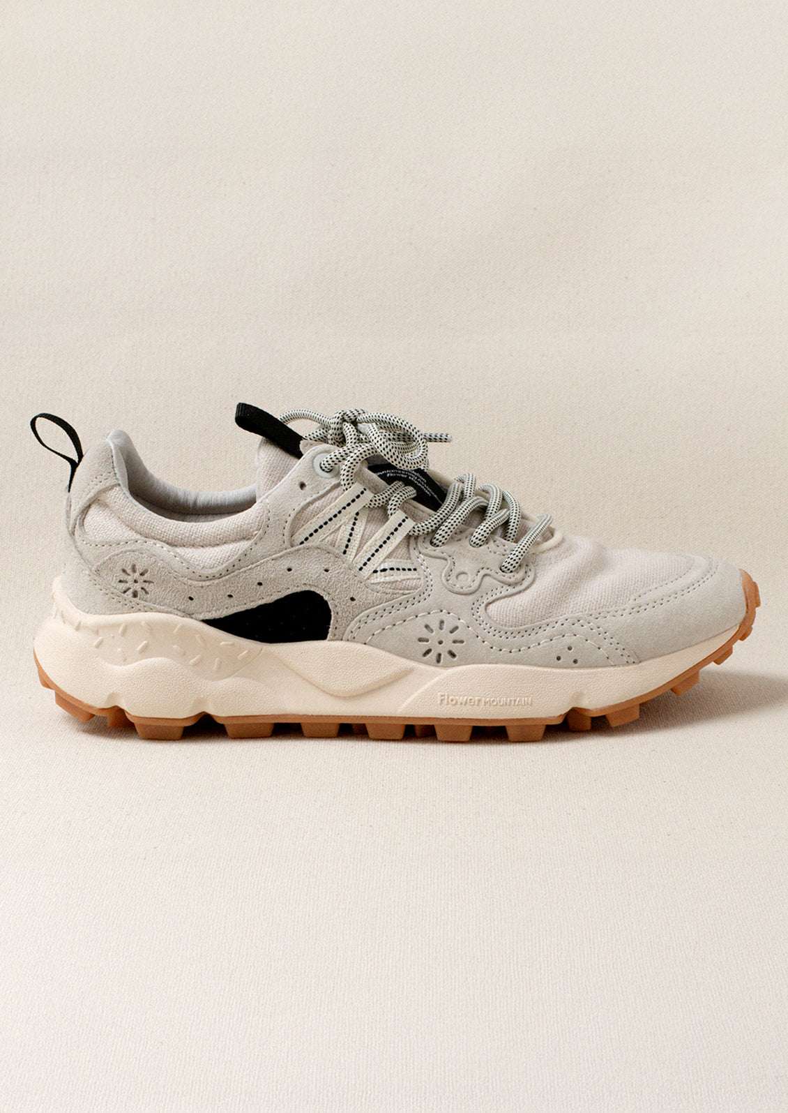 A pair of sporty sneakers in neutral colors with flower cutout detailing.