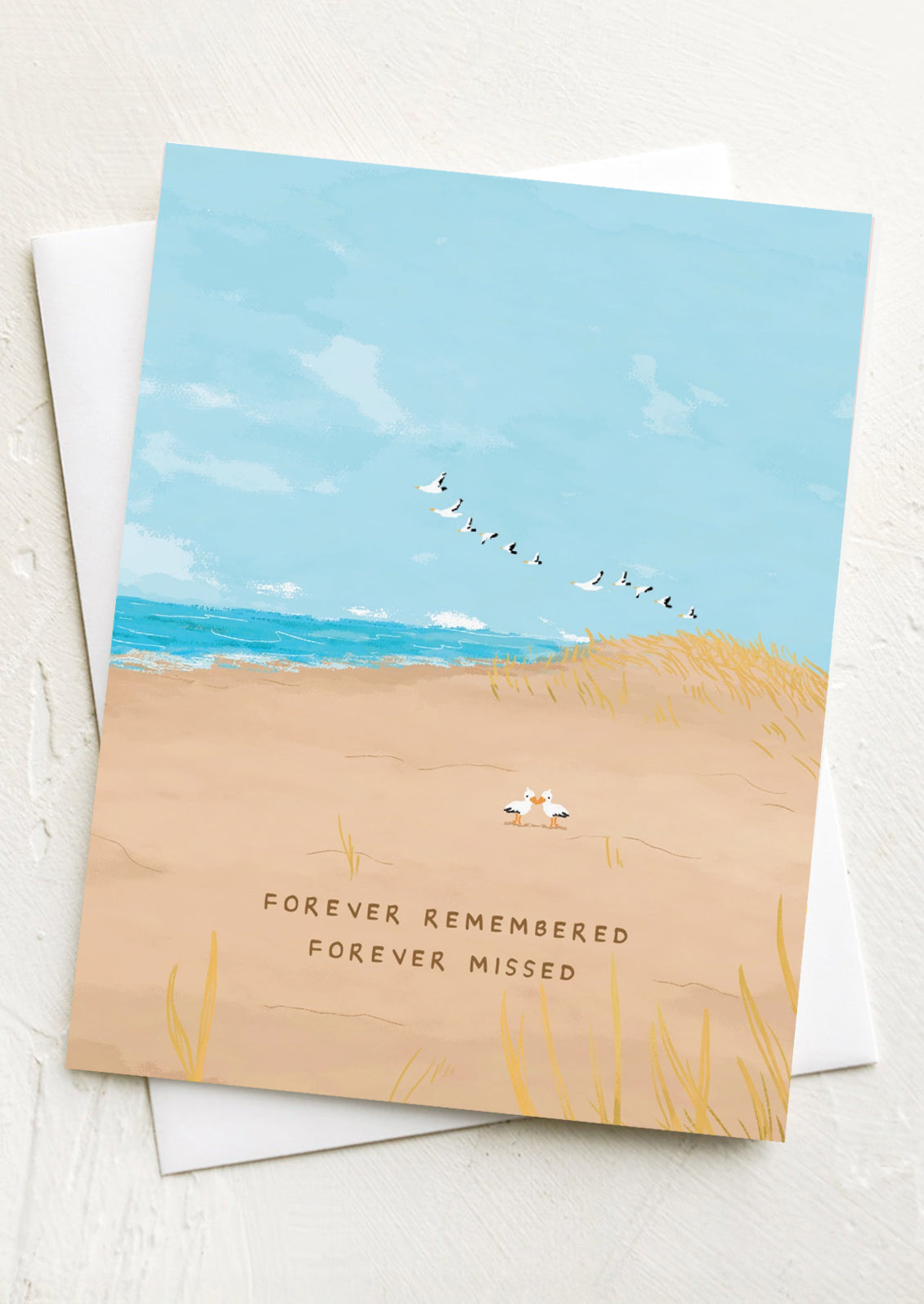 A greeting card with illustration of seagulls on a beach, text reads "Forever Remembered Forever Missed".