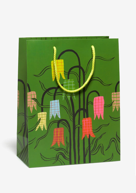 Green gift bag with colorful floral design and yellow handle.