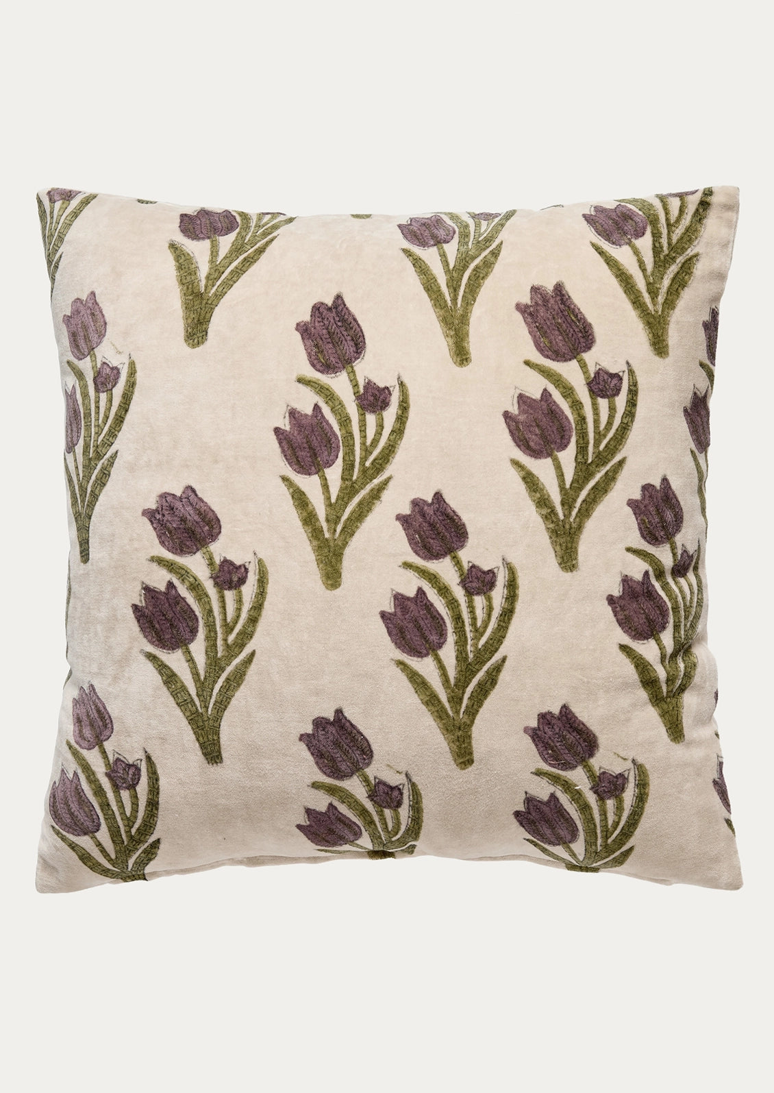 A square decorative throw pillow featuring a repeating pattern of embroidered purple tulips with green stems on a textured cream velvet fabric, set against a plain light gray background.