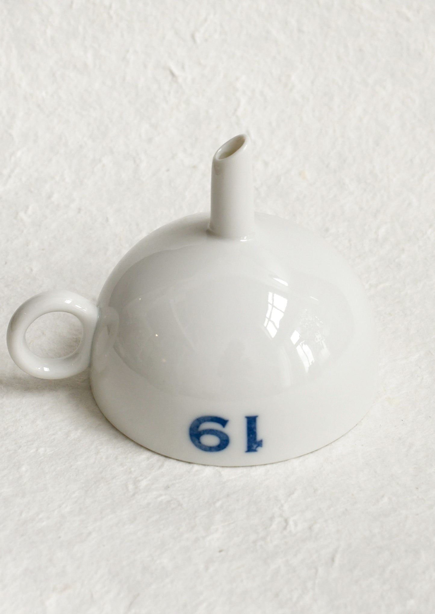 A ceramic funnel in white with printed blue text.