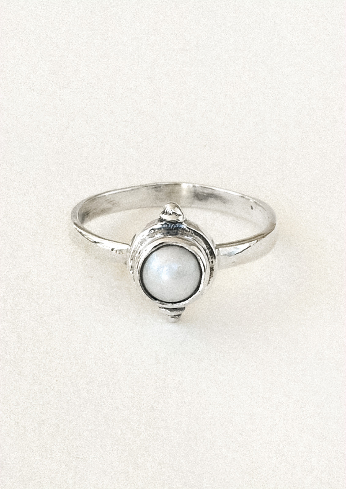 A sterling silver ring with a faux pearl in the center.