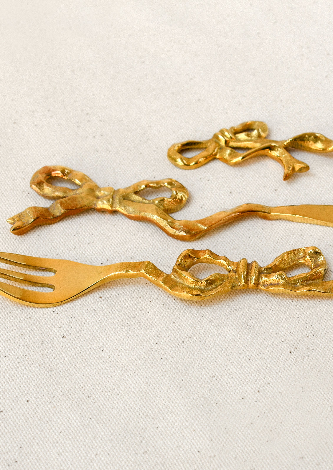 Brass canapé utensils with a bow shaped design.
