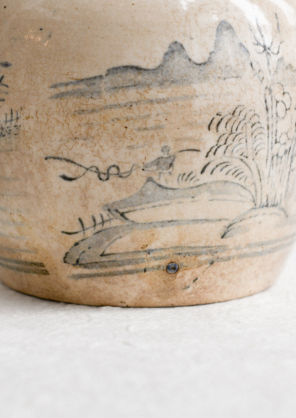 An aged stoneware ginger jar in beige patina with scenic scene in blue.