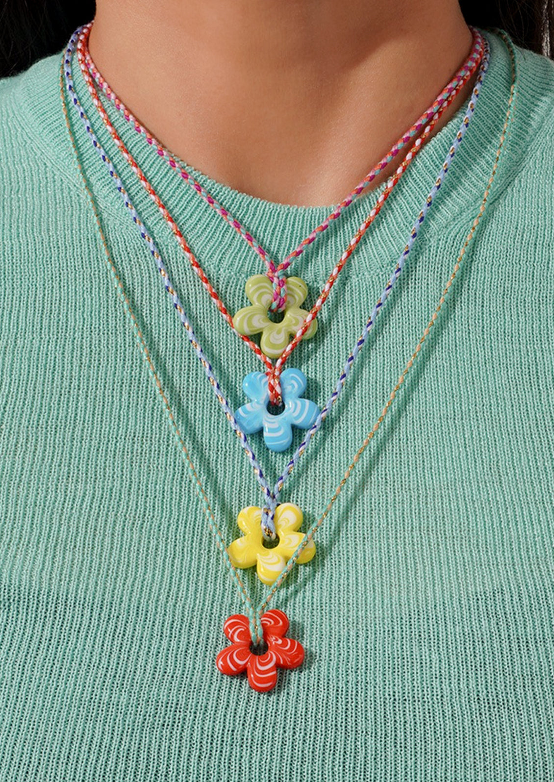 A women wearing 4 colorful glass flower pendant necklaces.
