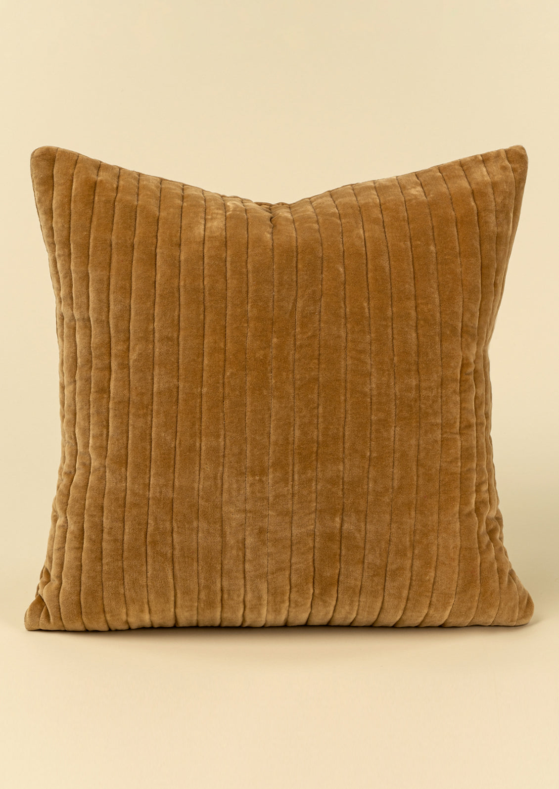 A square brown velvet throw pillow with vertical ribbed quilting.