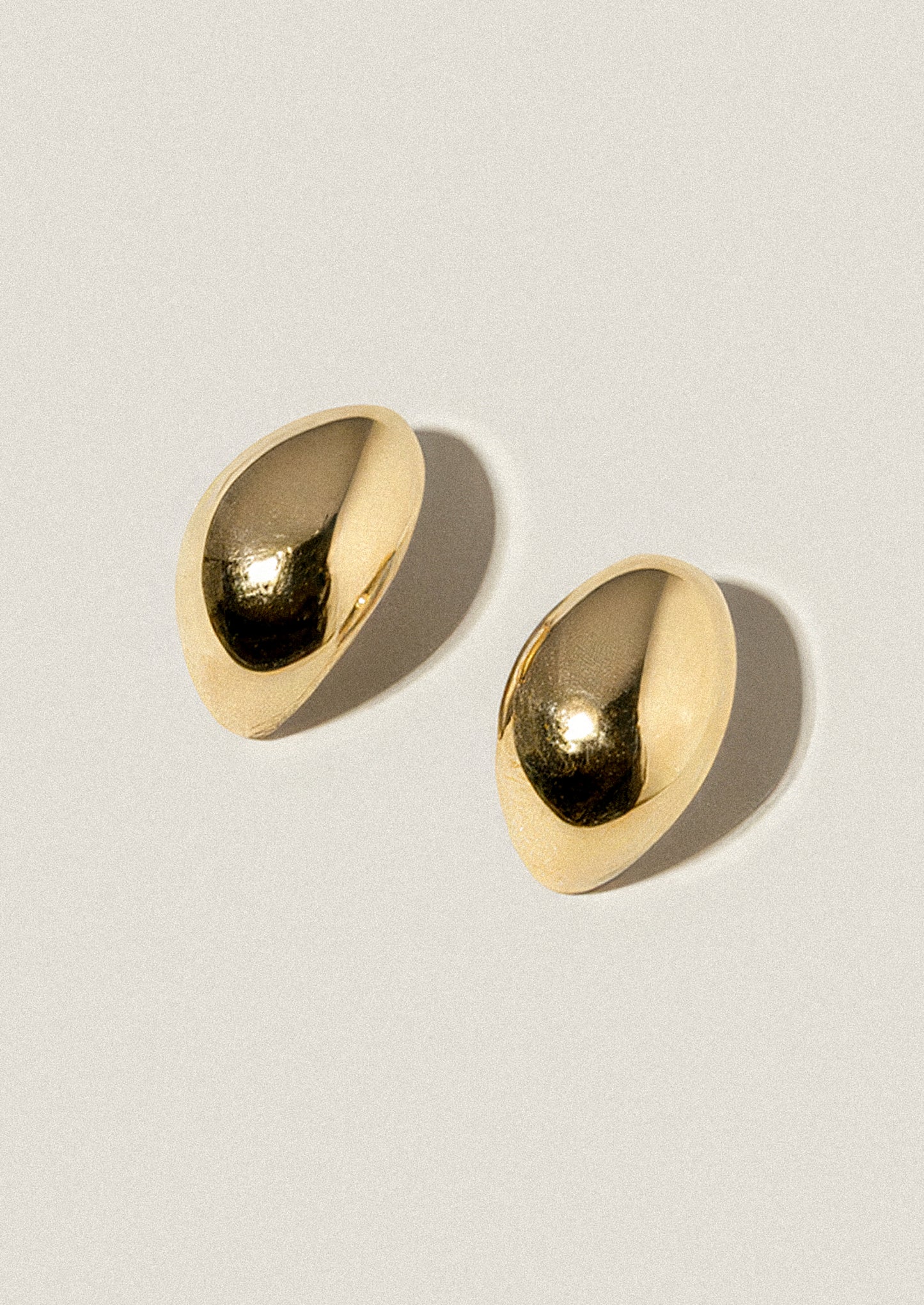 Pair of gold earrings on a light gray background