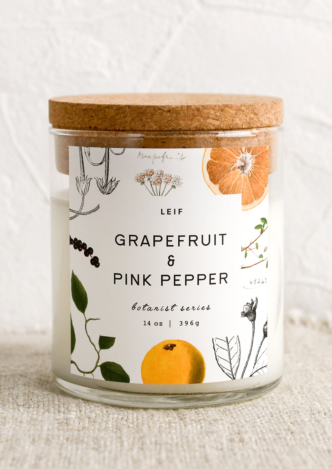 A glass jar candle in Grapefruit & Pink Pepper scent with botanical print label.