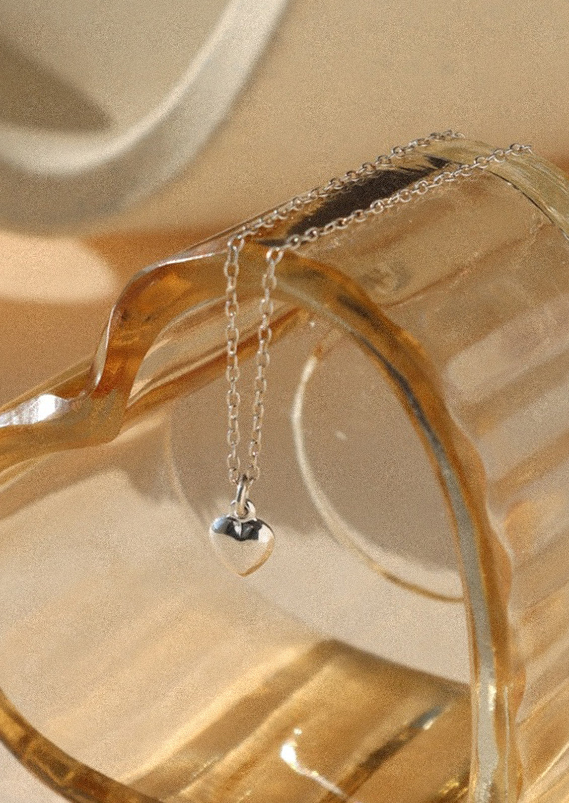 A sterling silver necklace with a small heart charm.